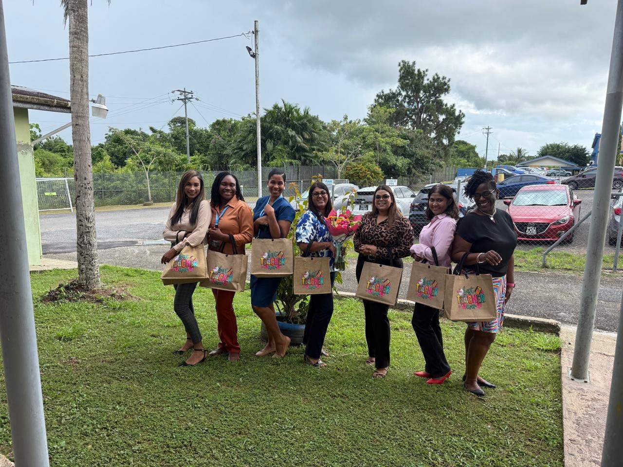 Seven teachers standing outdoors holding tote bags